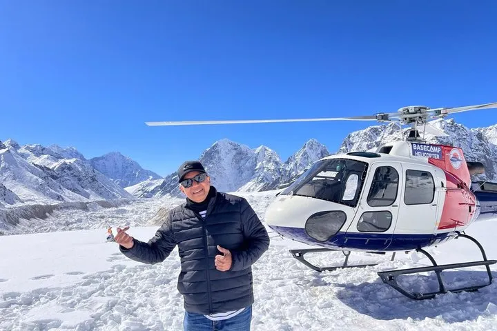 Passenger beside a white helicopter on the snow at Kala Patthar on an Everest climbing tour by helicopter, Nepal