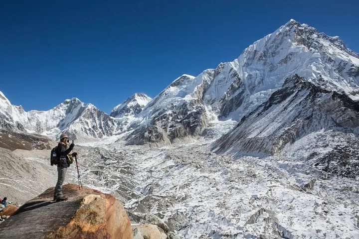 Trekker on a rock above the Khumbu Glacier with Nuptse behind on an Everest climbing tour to Everest Base Camp, Nepal